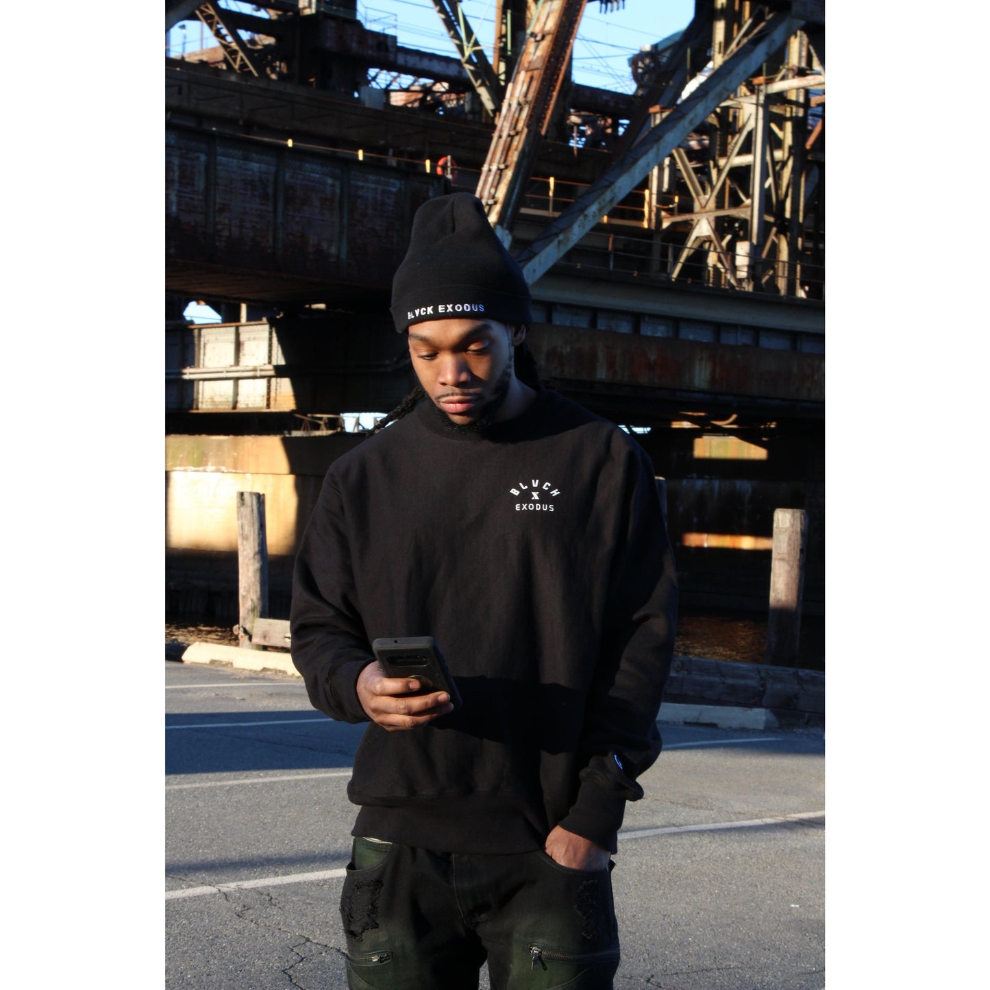 black male in Black crewneck sweatshirt with a white Blvck Exodus logo on the chest. Black Blvck Exodus hat