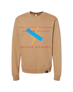 Men's tan crewneck sweatshirt featuring a bold graphic design with a blue stripe crossing out a lightning bolt and the phrase "Don't Listen to Anyone Everyone is Scared" in red text. The "Blvck Exodus" logo is displayed below the graphic.